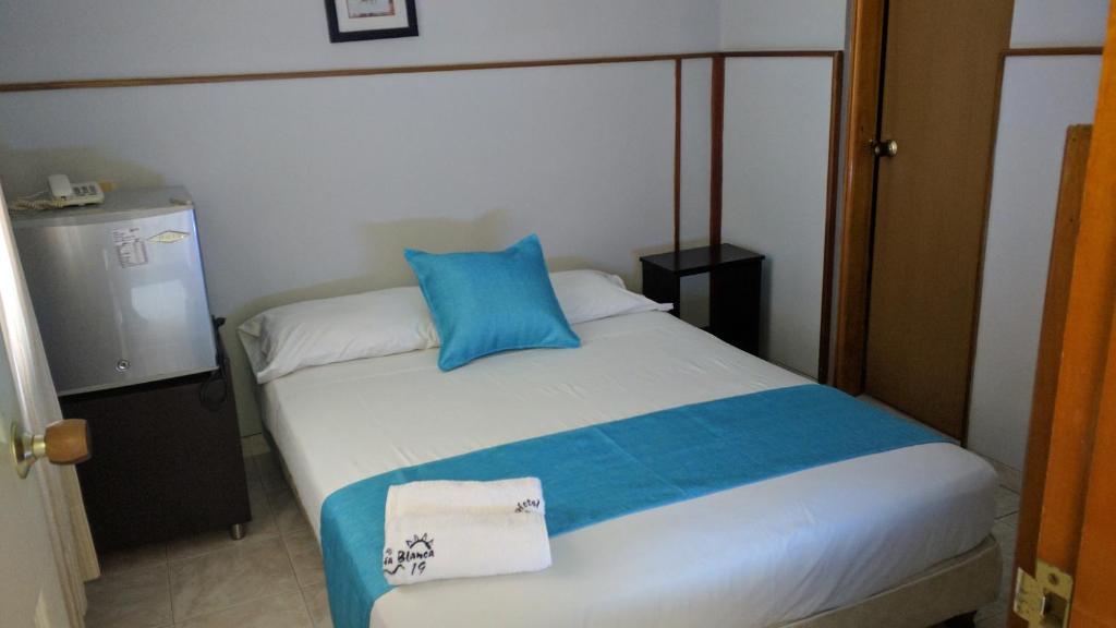 a bedroom with a bed with a blue pillow on it at Hotel Bahia Blanca Santa Marta Frente al Mar in Santa Marta