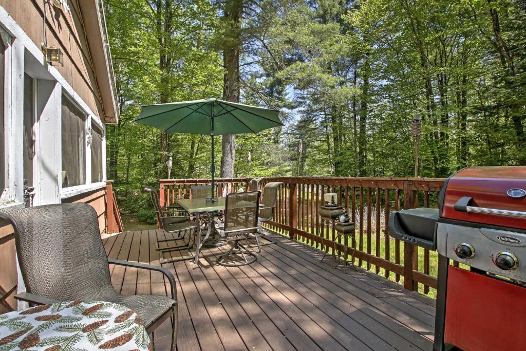 une terrasse en bois avec un grill et un parasol dans l'établissement Pet-Friendly Cabin with Fire Pit, BBQ and Great Deck!, à Williamsburg