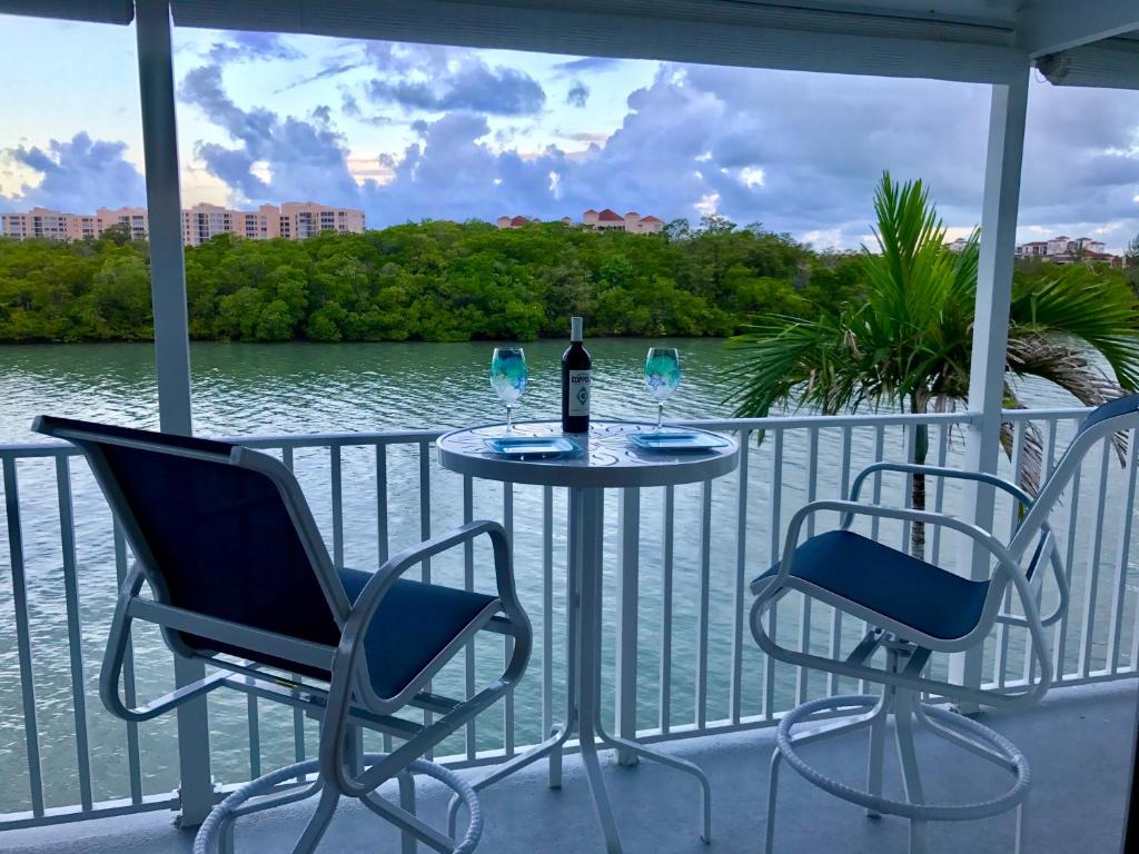 a table with two chairs and a bottle of wine on a balcony at Waterfront Marco Island Retreat with Shared Docks in Marco Island