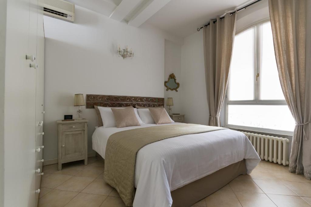 ein weißes Schlafzimmer mit einem großen Bett und einem Fenster in der Unterkunft Casa Letizia in Bologna