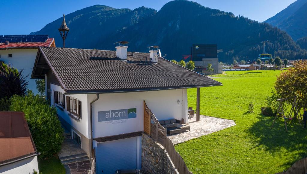 a small white house with mountains in the background at Ahorn Chalet in Mayrhofen