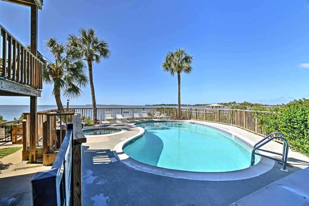 a swimming pool next to the beach with palm trees at Beachfront Cedar Key Condo with Pool, Spa and Views! in Cedar Key
