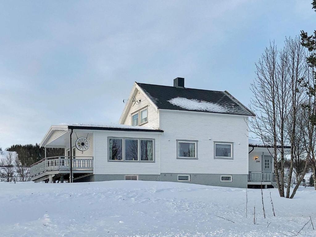 uma casa branca com neve no chão em Holiday home Svensby III em Svensby