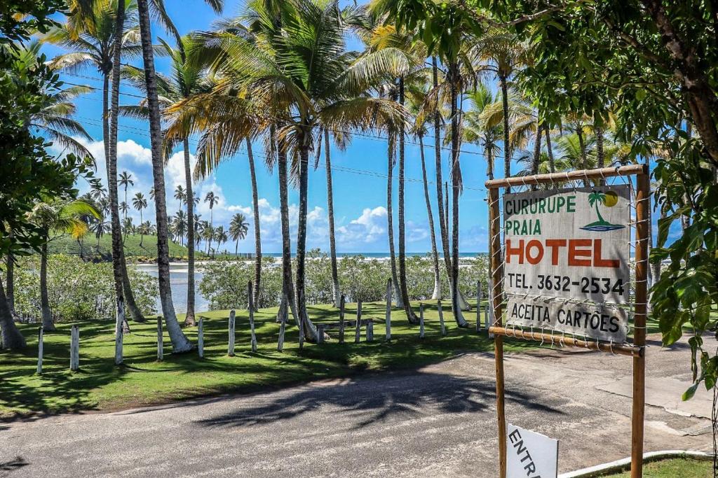 un cartello per un hotel su una spiaggia con palme di Cururupe Praia Hotel a Ilhéus