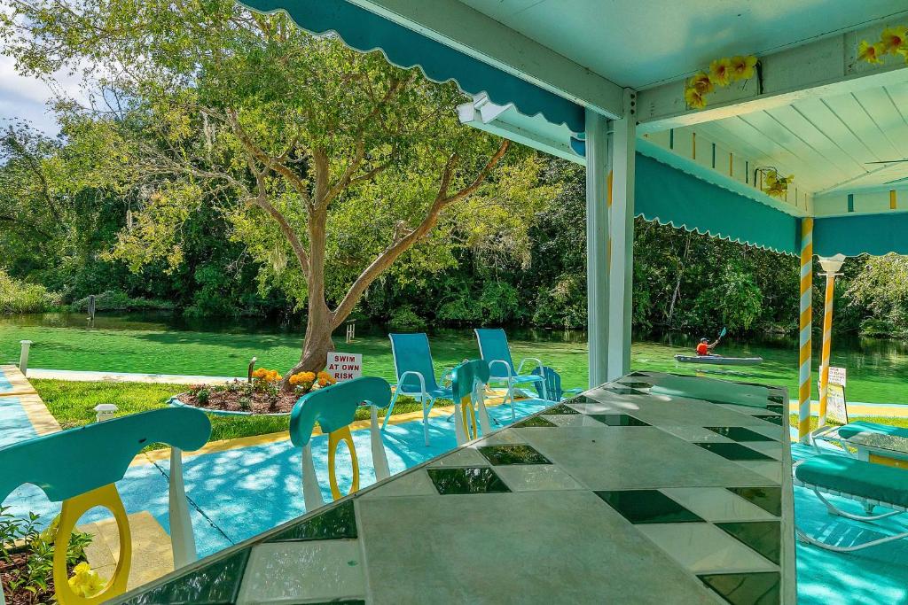 eine Terrasse mit Stühlen, einem Tisch und einem Pool in der Unterkunft Pams Mermaid House with Riverfront Yard and Lanai! in Weeki Wachee