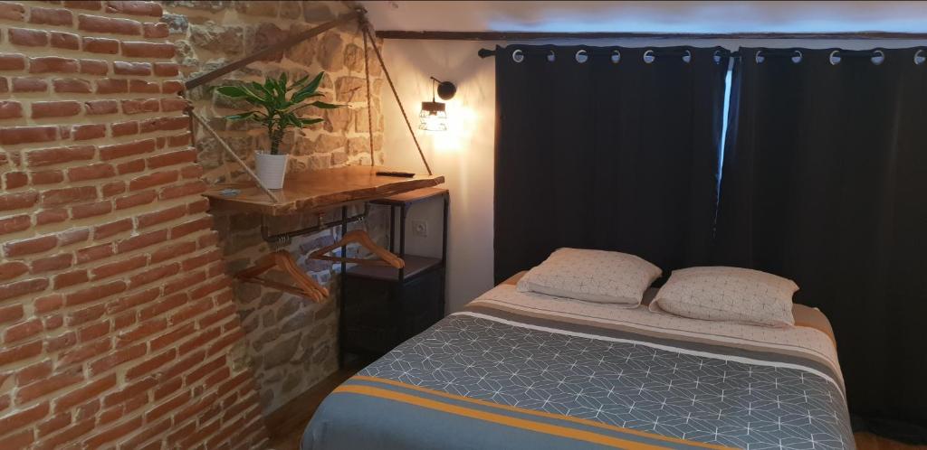 een slaapkamer met een bed en een bakstenen muur bij Atypical Flat in Charleville-Mézières