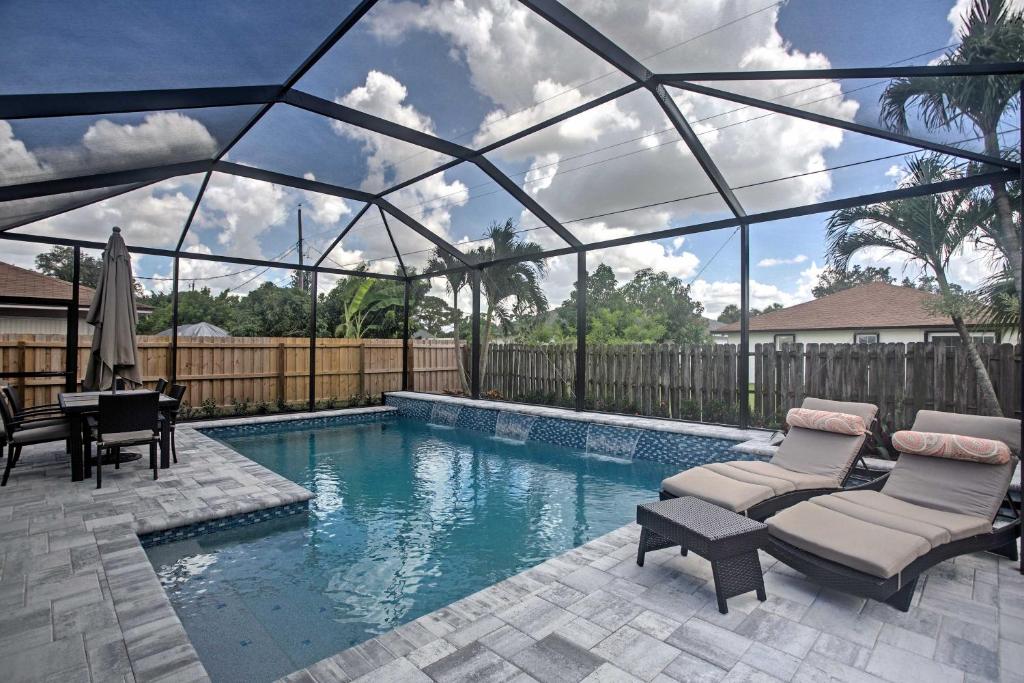 uma piscina com duas espreguiçadeiras e uma mesa em Naples Home with Lanai and Pool Near Vanderbilt Beach! em Naples