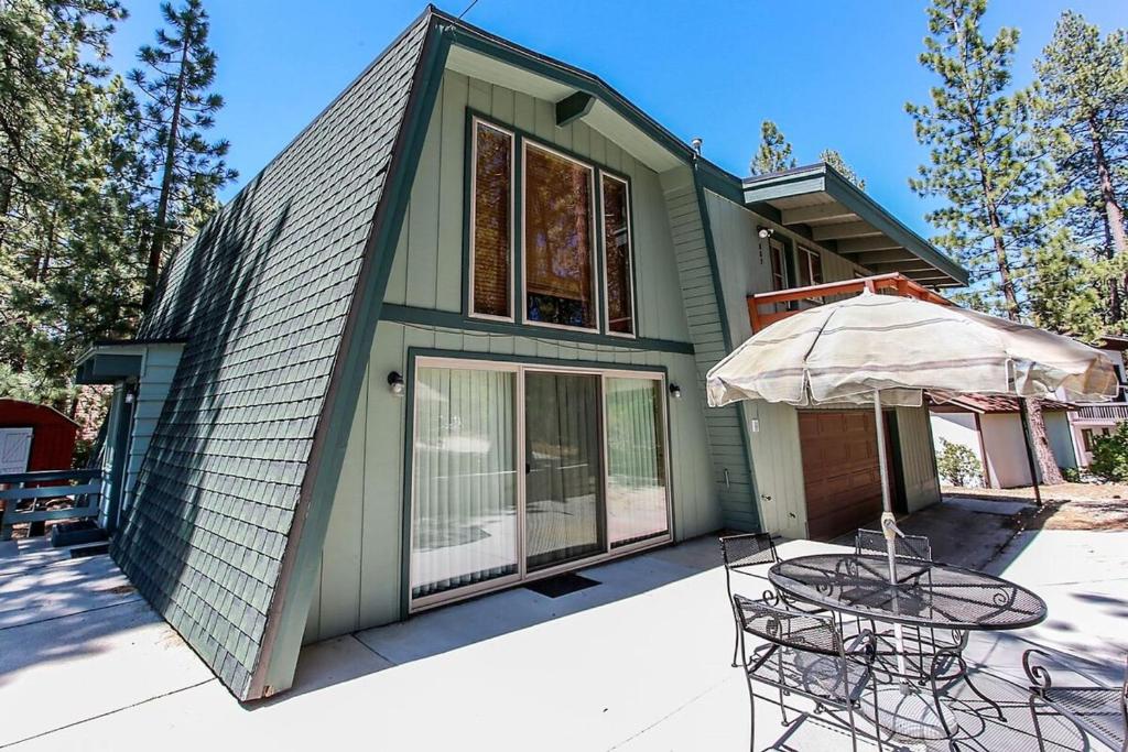 a green house with a table and an umbrella at Switzerland Ski Chalet-845 by Big Bear Vacations in Big Bear Lake