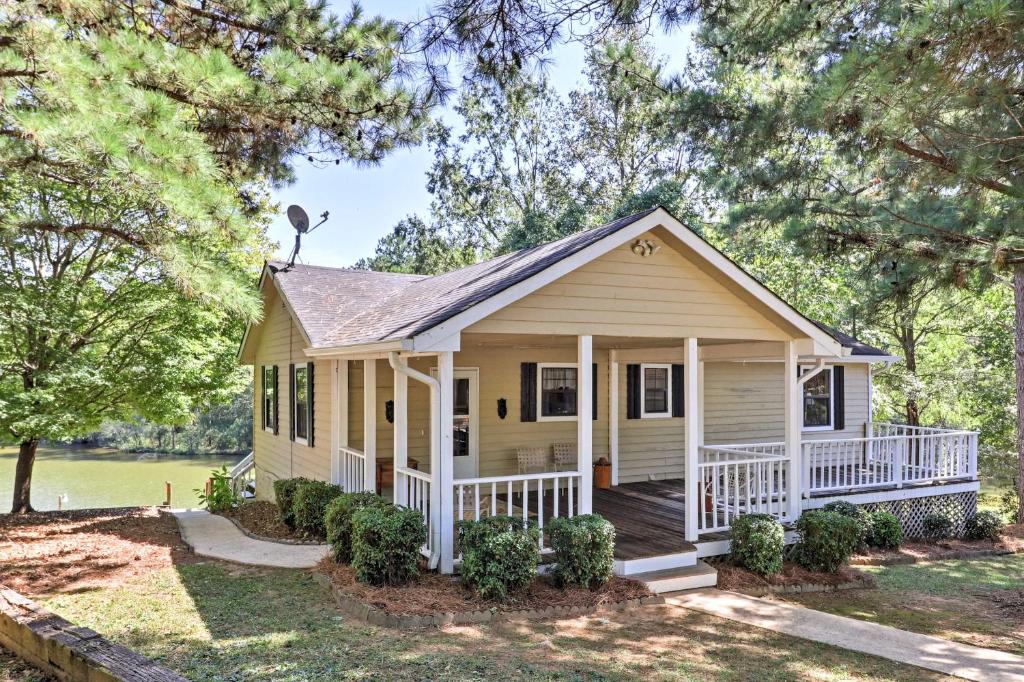 a small yellow house with a porch at Lakefront Cottage with Private Hot Tub! in Buckhead