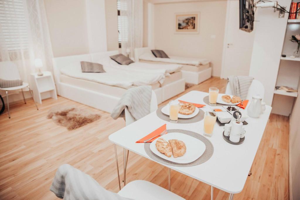 ein weißes Wohnzimmer mit einem Tisch mit Essen drauf in der Unterkunft Shkodra apartment with amazing view in the city center in Shkodra