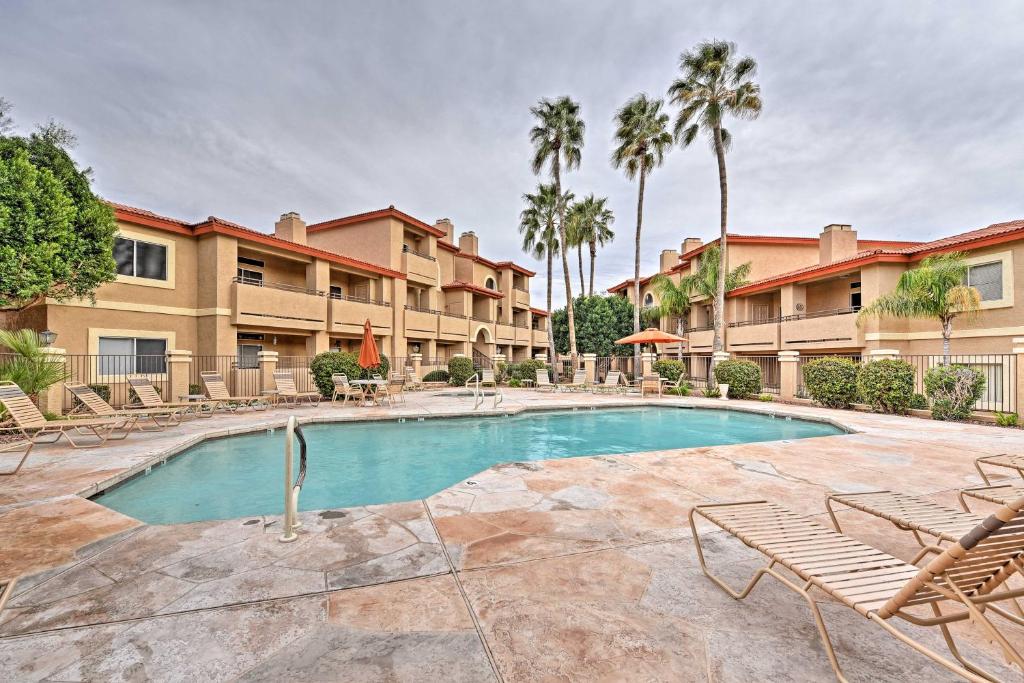 a swimming pool in a courtyard with chairs and palm trees at Phoenix Condo with Balcony and Spa - 14 Mi to Downtown in Phoenix