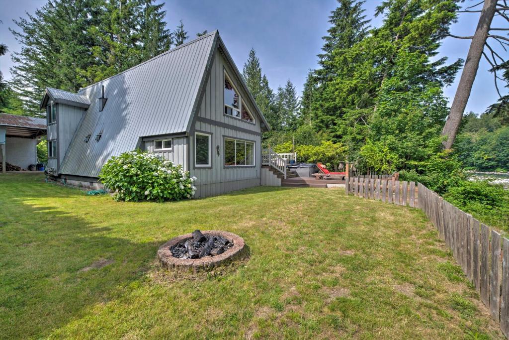 a house with a fire pit in the yard at Riverfront Gold Bar Cabin with Hot Tub and Mtn Views! in Gold Bar