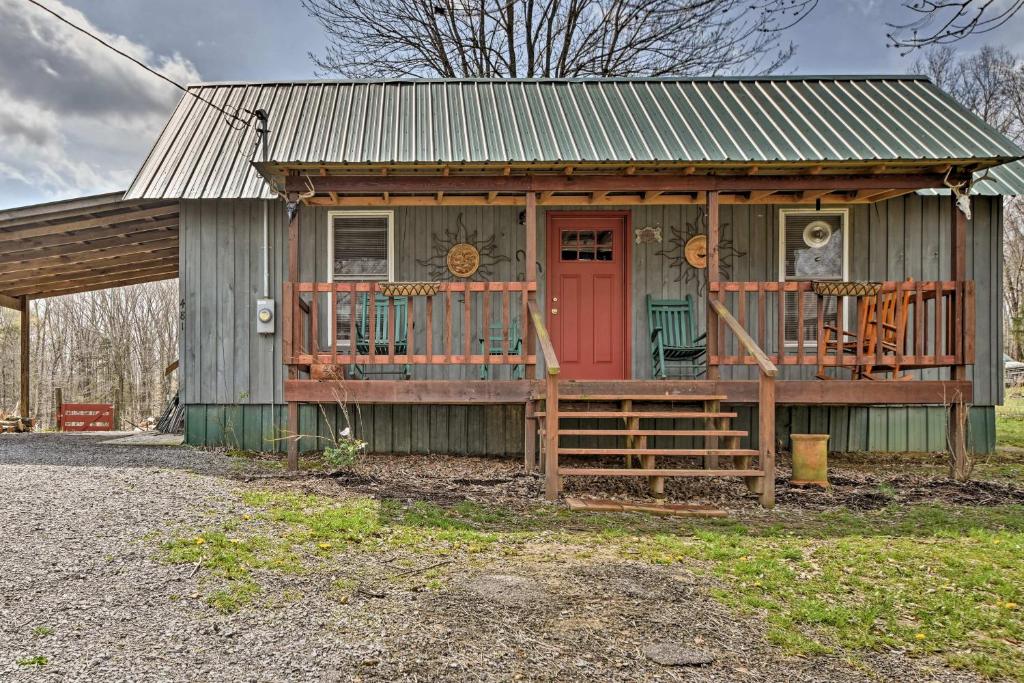 una pequeña casa con puerta roja y porche en Remote Kentucky Cabin with Fire Pit and 2 Ponds en New Concord