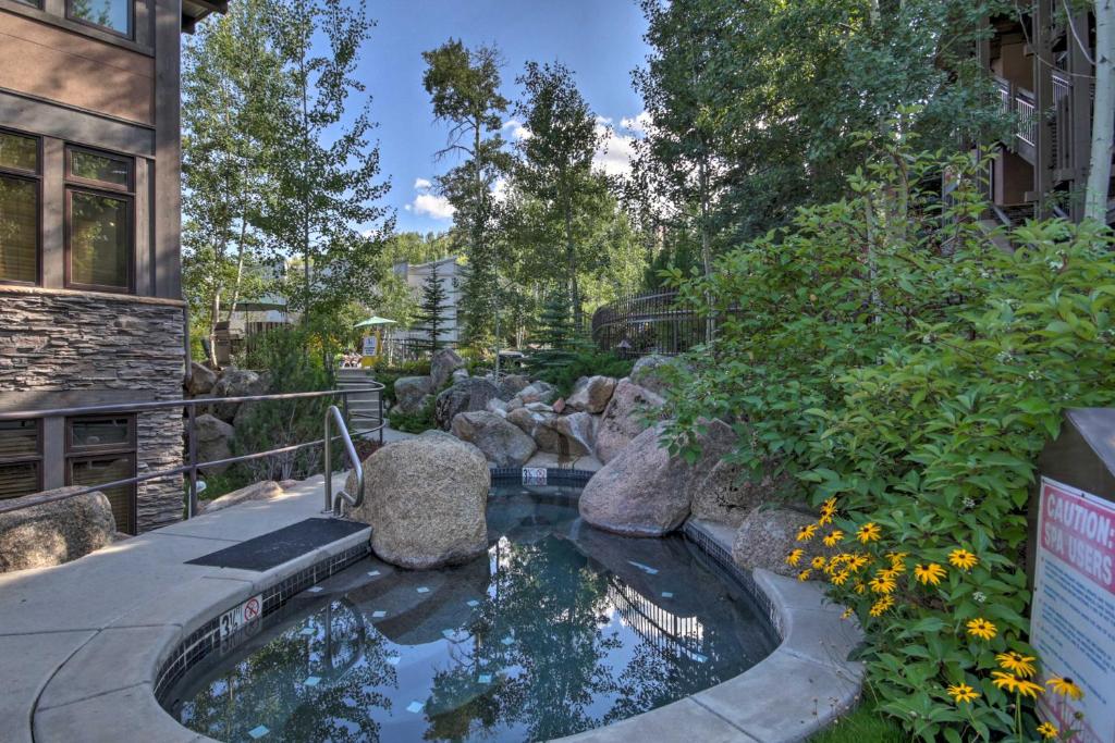 un estanque koi en un jardín junto a un edificio en Ski-InandOut Oversized Aspen Studio with Pool and Hot Tub, en Snowmass Village