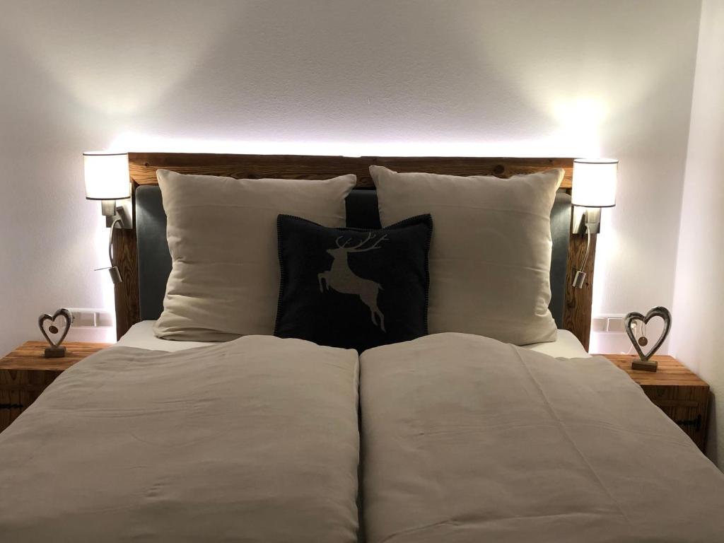 1 cama con almohadas blancas y 2 lámparas en ambos lados en Ferienwohnung Winklblick en Reit im Winkl