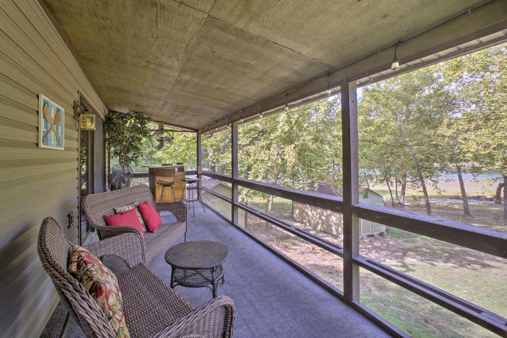 a screened in porch with a couch and chairs at Lakefront Table Rock Home with Fire Pit! in Golden