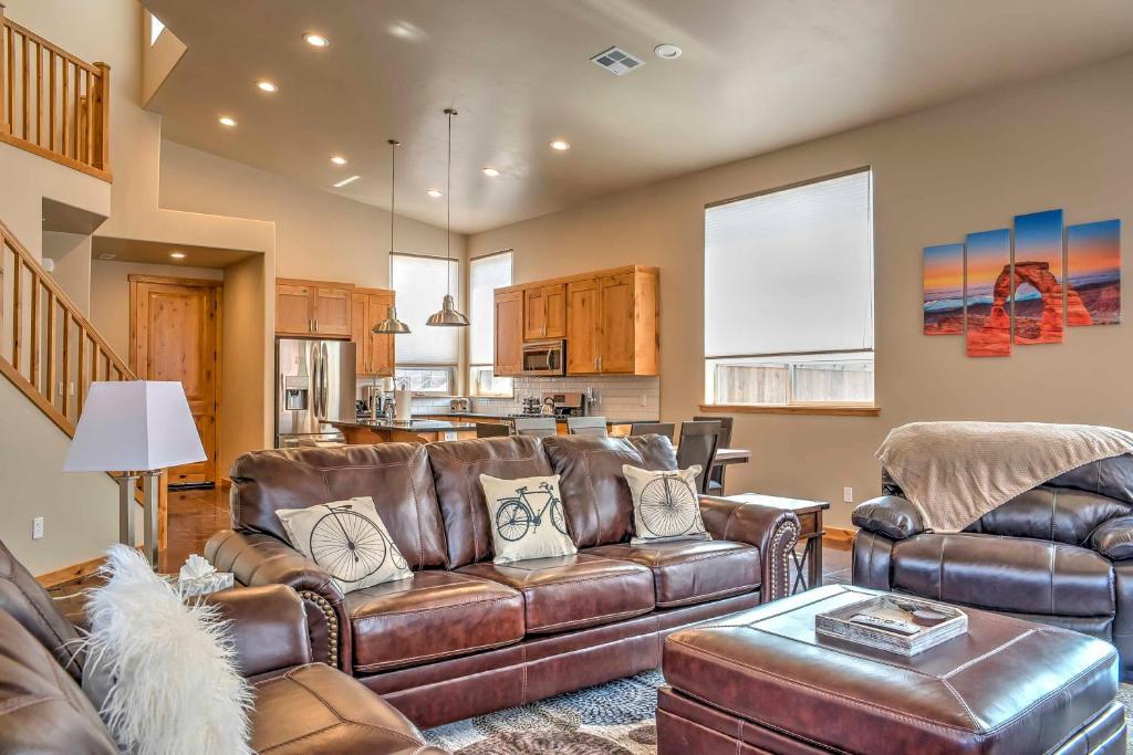 a living room with leather furniture and a kitchen at Modern Moab Townhome with Private Hot Tub and Patio! in Moab