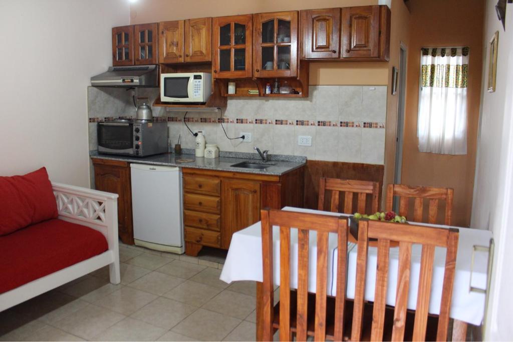 eine kleine Küche mit Holzschränken und einer roten Couch in der Unterkunft Estación Aeropuerto Ezeiza in Partido Lomas de Zamora