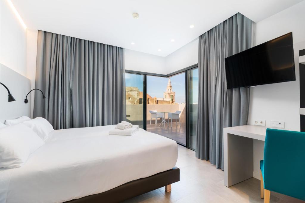 um quarto de hotel com uma cama, uma secretária e uma janela em Dormos Hotel em Cádiz