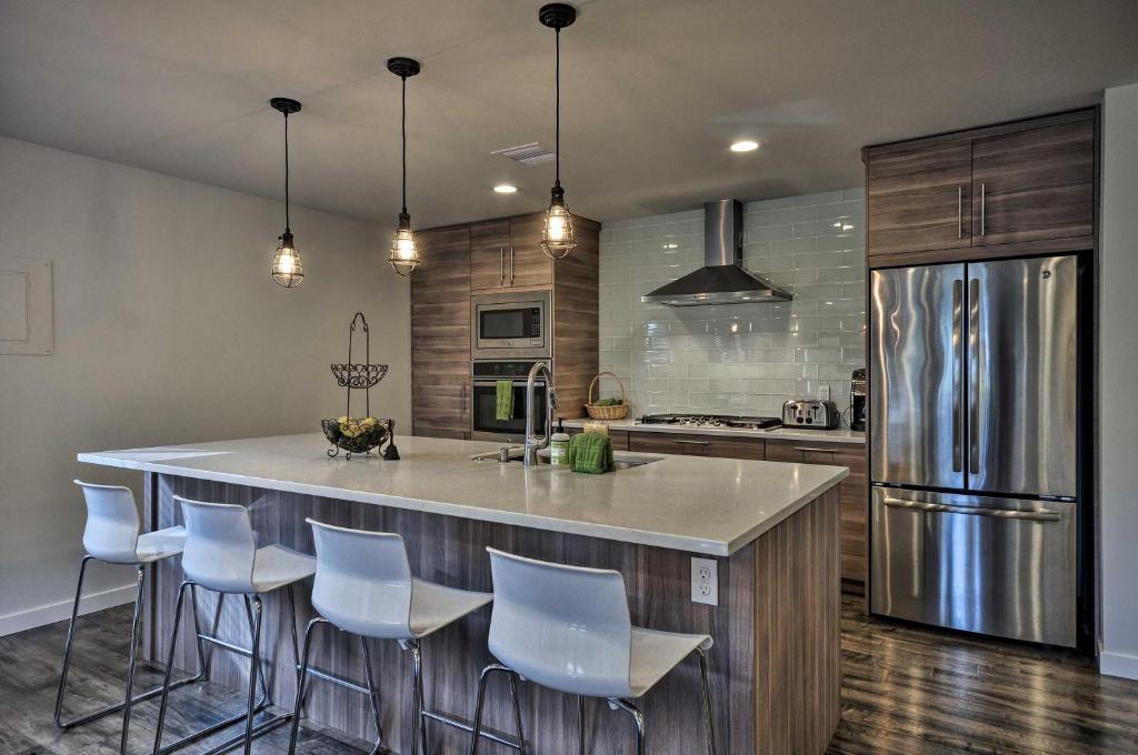 a kitchen with a large island with white bar stools at Sleek Riverfront Condo on Pier in Downtown Astoria in Astoria, Oregon