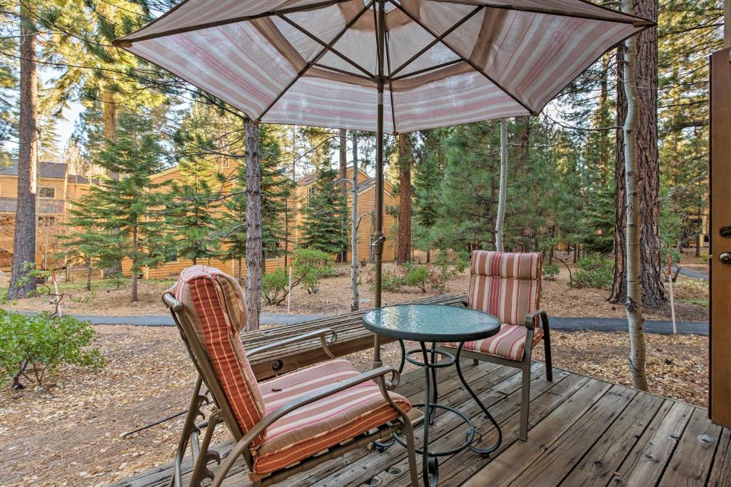 斜坡村的住宿－Corner-Unit Condo with Grill Walk to Lake Tahoe!，天井配有桌子、两把椅子和遮阳伞。