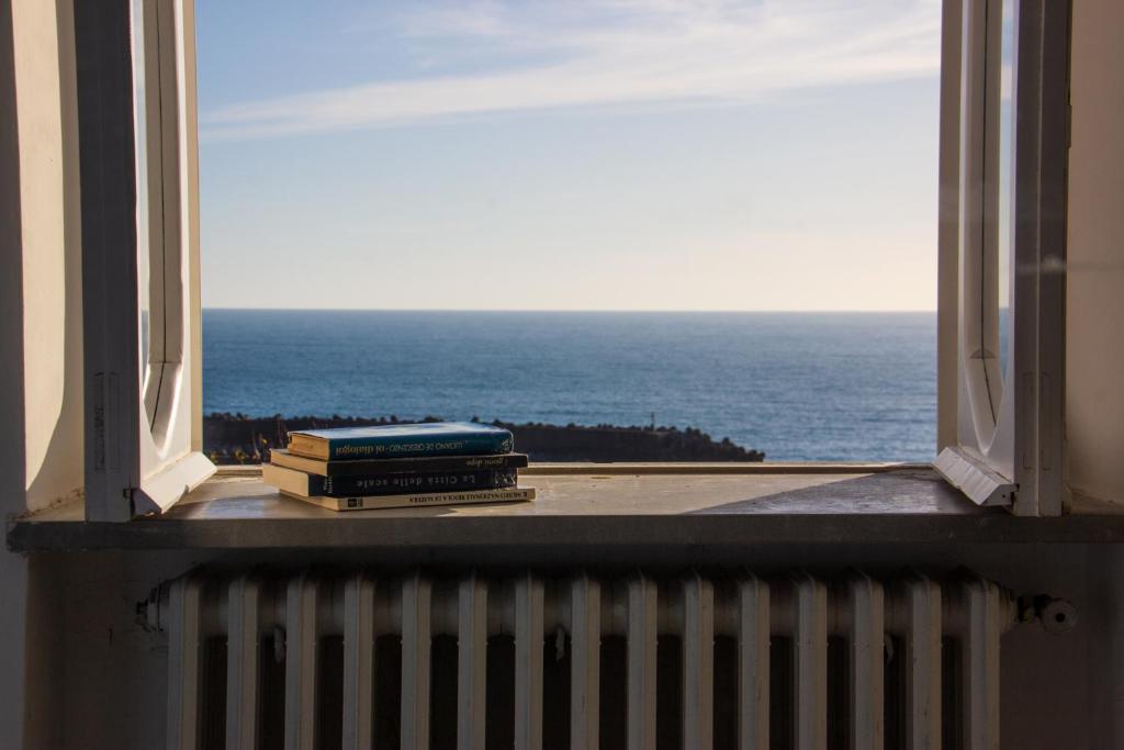 Dois livros sentados no peitoril da janela, a olhar para o oceano. em Dimore Santojanni - La Casa sul Porto em Maratea