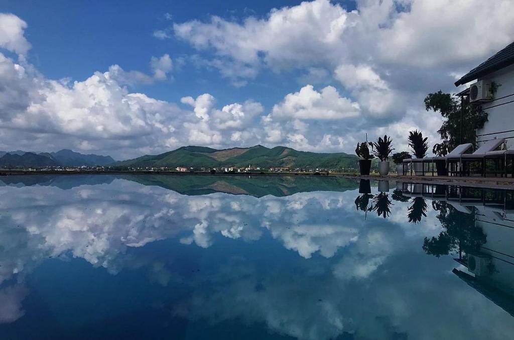 a large body of water with a building and mountains at Karst Villas Phong Nha in Phong Nha