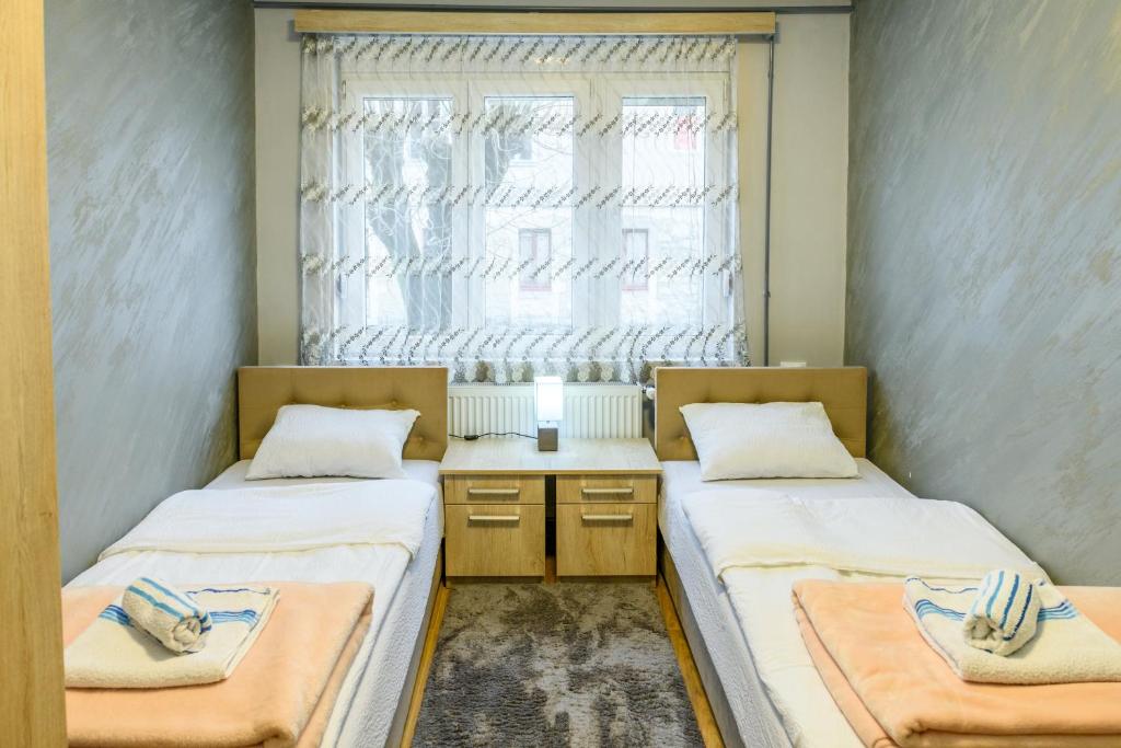 two beds in a room with a window at Vujisić Apartment in the City Center in Kolašin