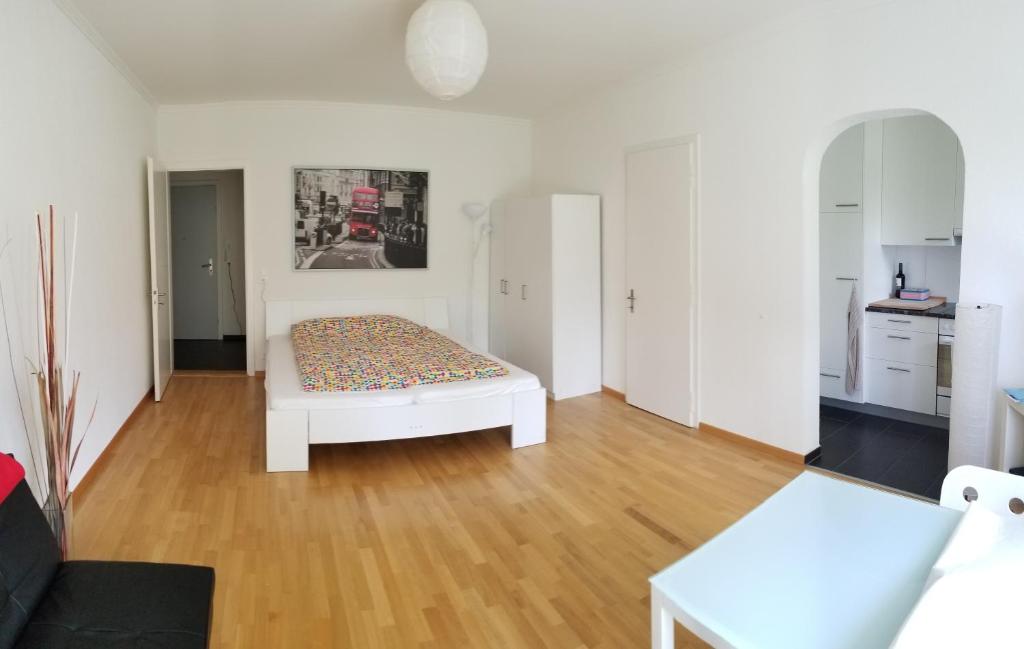 - un salon avec un lit dans une pièce blanche dans l'établissement HSH Monbijou - Serviced Junior Suite with balcony Bern City by HSH Hotel Serviced Home, à Berne