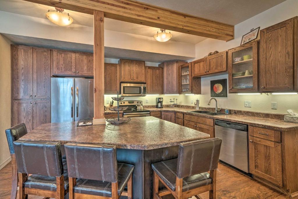 a kitchen with wooden cabinets and a large island with chairs at Updated Townhome with Hot Tub - Walk to Downtown! in Red Lodge