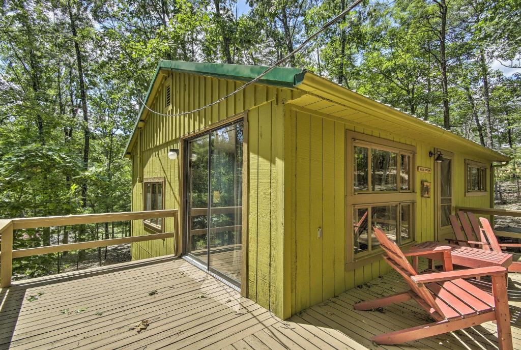 a yellow tiny house with two chairs on a deck at Lucas McCain Cabin 5 Mi to Raystown Lake Launch! in Huntingdon