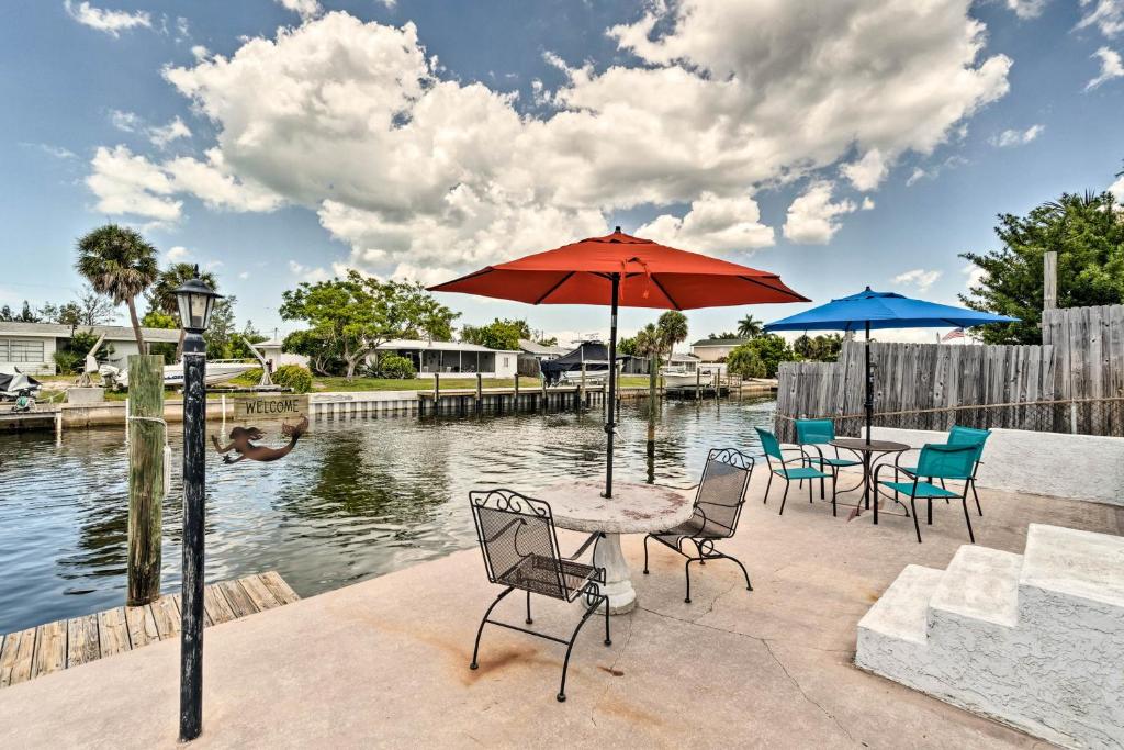 eine Terrasse mit Tischen und Sonnenschirmen neben dem Wasser in der Unterkunft Canalfront Bradenton Home with Dock and Pool! in Bradenton
