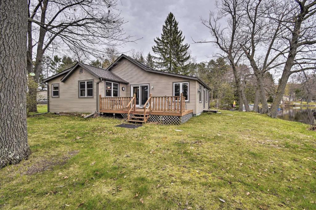 a small house on a hill with a yard at Lakefront Home with Seasonal Dock - 2 mi to Skiing! in Wautoma