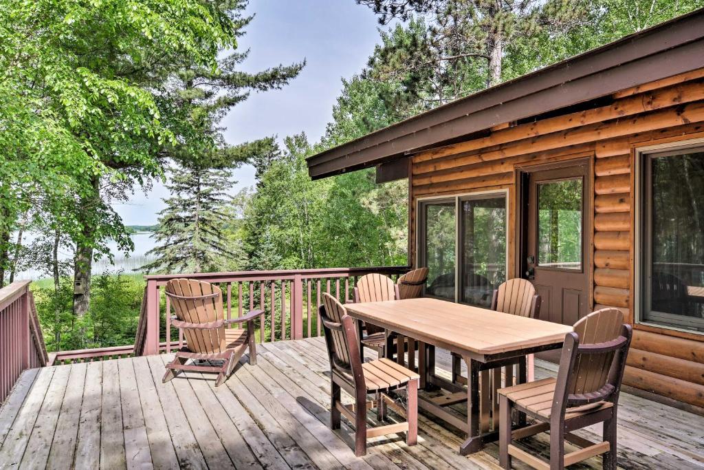 a wooden deck with a table and chairs on it at Rustic Cozy Cabin on Island Lake with Fire Pit, Dock in Arago