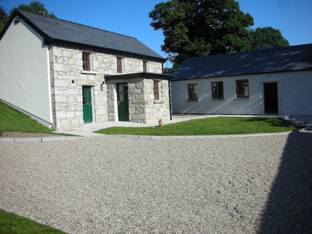 a stone house with a gravel driveway in front of it at Green Adventure EcoHostel in Clonmore