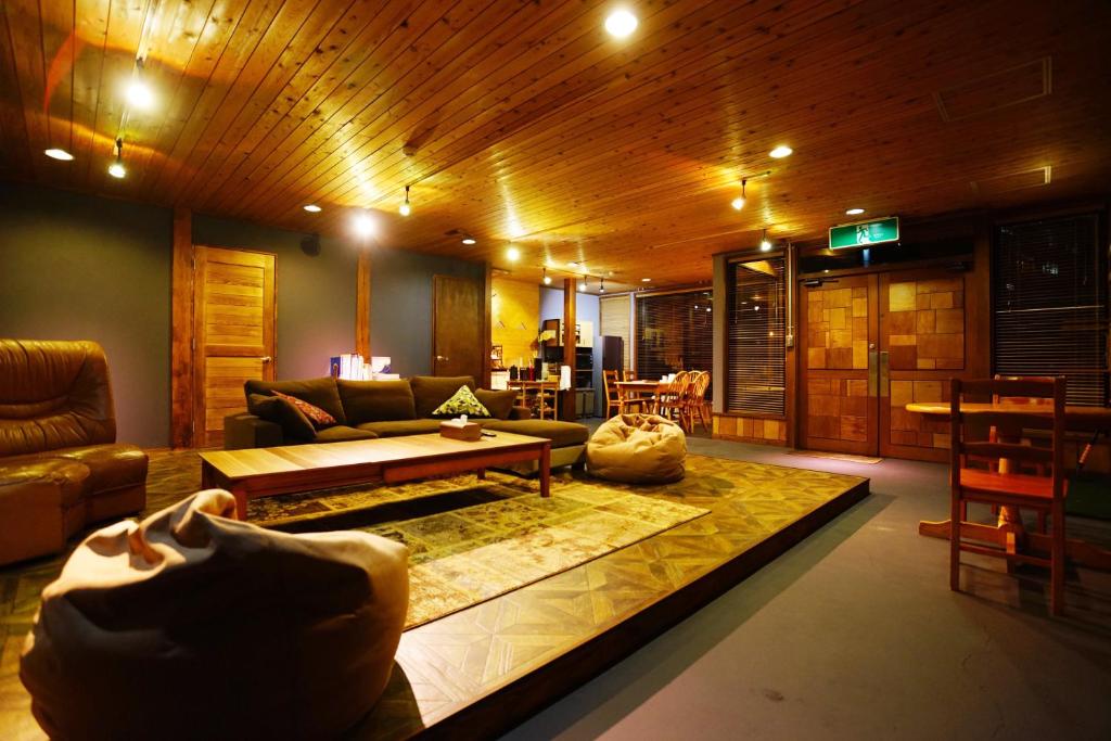 sala de estar con sofá y mesa en HAKUBA LODGE OMUSUBI en Otari