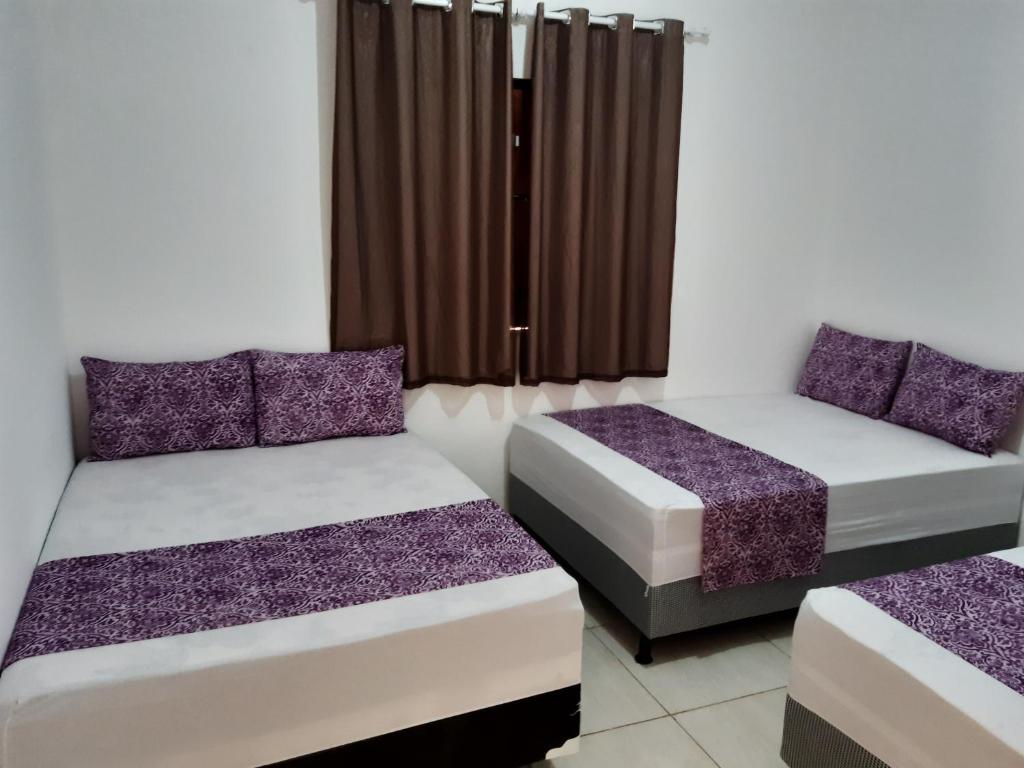 two beds in a room with purple and white at Casa de Temporada Illôa in Canindé de São Francisco