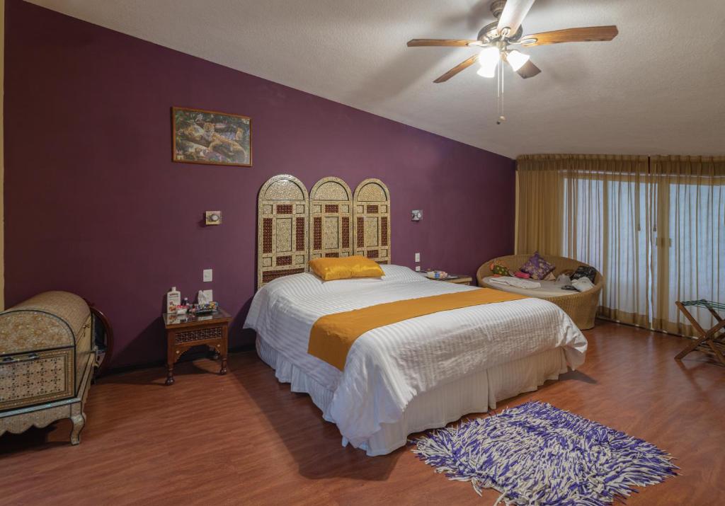 1 dormitorio con 1 cama grande y paredes moradas en Casa Shalom Puebla, en Puebla