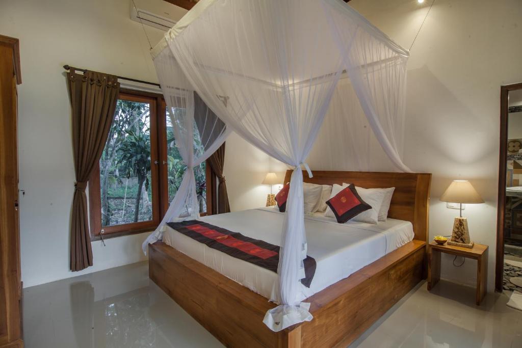 - une chambre avec un lit à baldaquin et une fenêtre dans l'établissement Abimana Ubud, à Ubud