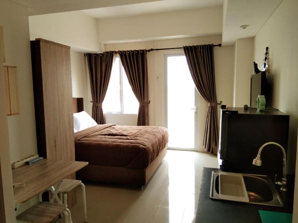 um quarto com uma cama e uma televisão num quarto em Bogor Icon Apartment em Kedunghalang