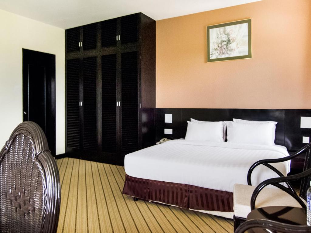 a bedroom with a large white bed and a chair at Perkasa Hotel Keningau in Keningau