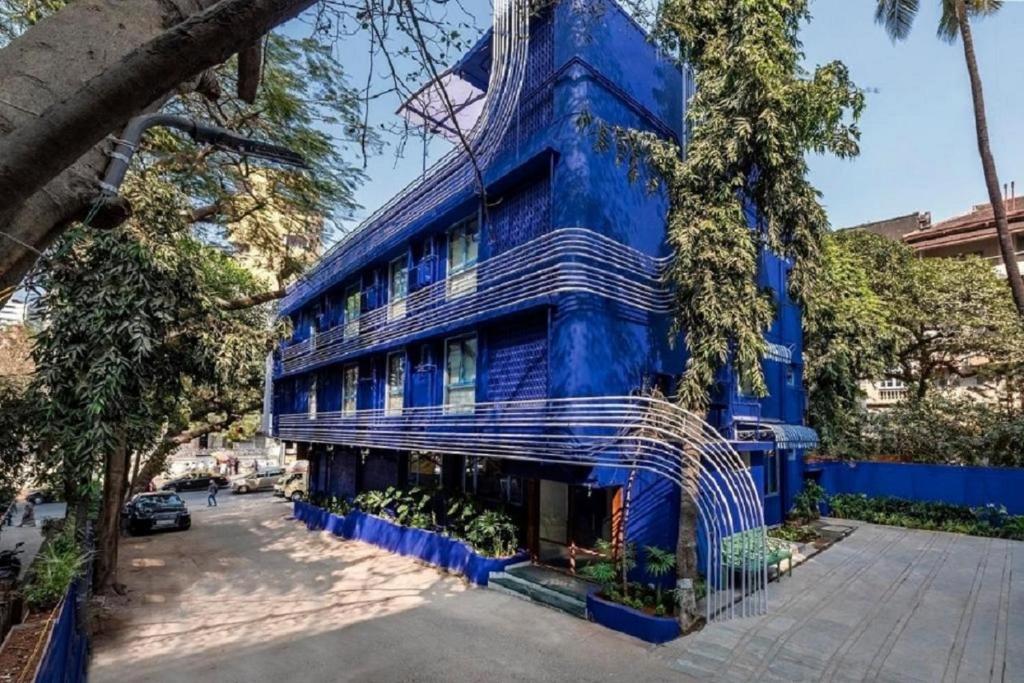 a blue building with a metal gate in front of it at Hotel Kemps Corner in Mumbai