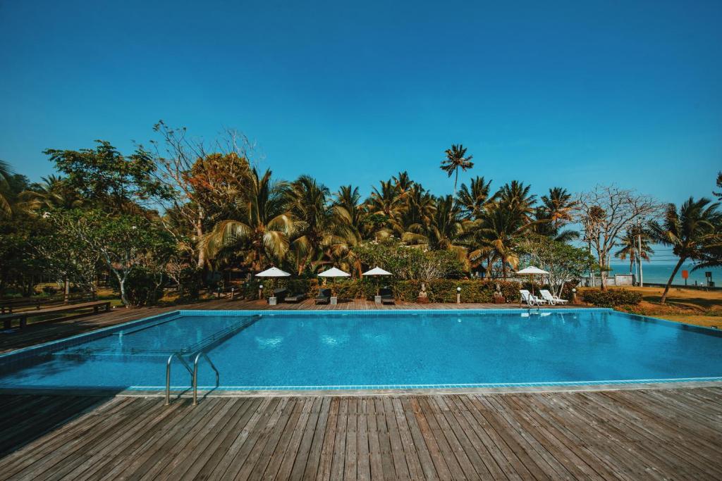 PathiuにあるNana Beach Hotel & Resortの- リゾート内のスイミングプール(椅子、パラソル付)