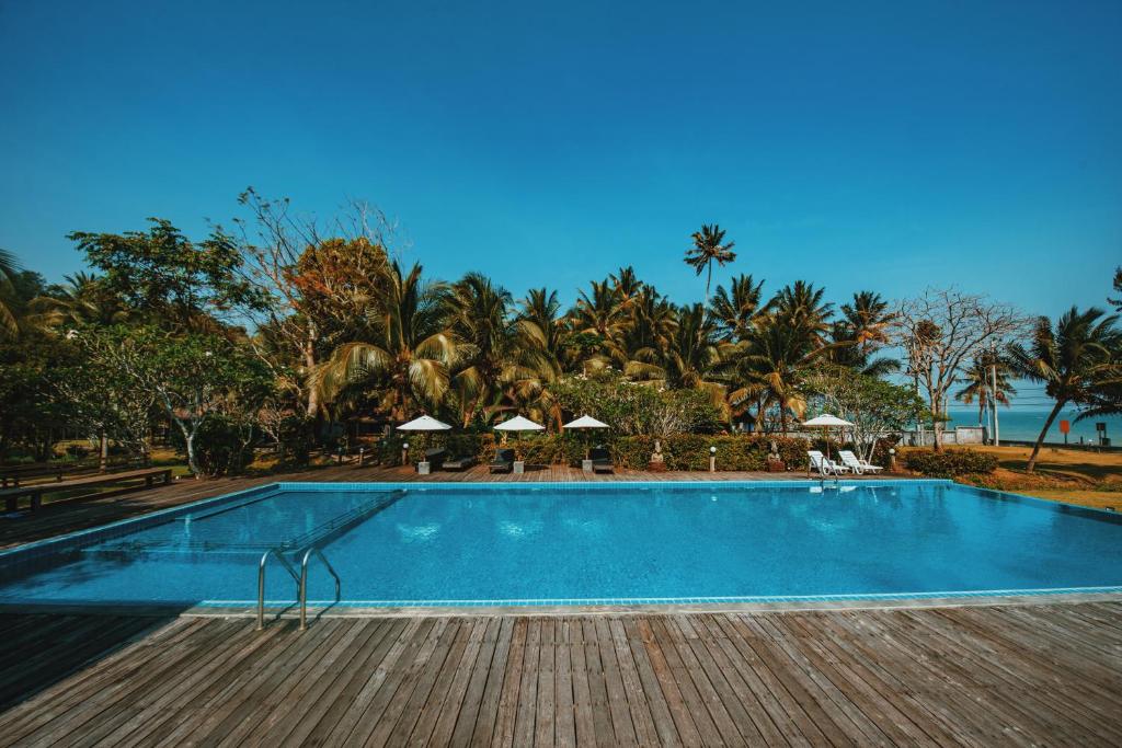 a swimming pool with chairs and umbrellas in a resort at Nana Beach Hotel & Resort in Pathiu