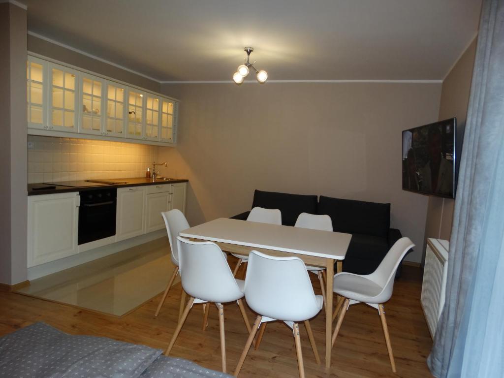 a kitchen and dining room with a table and white chairs at Apartamenty Miku in Krynica Zdrój