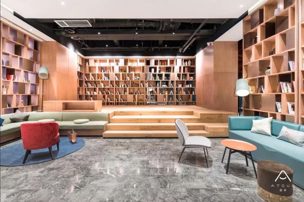 een bibliotheek met een bank, stoelen en boekenplanken bij Atour Hotel (Wuhan Sea World Tazihu Metro Station) in Wuhan