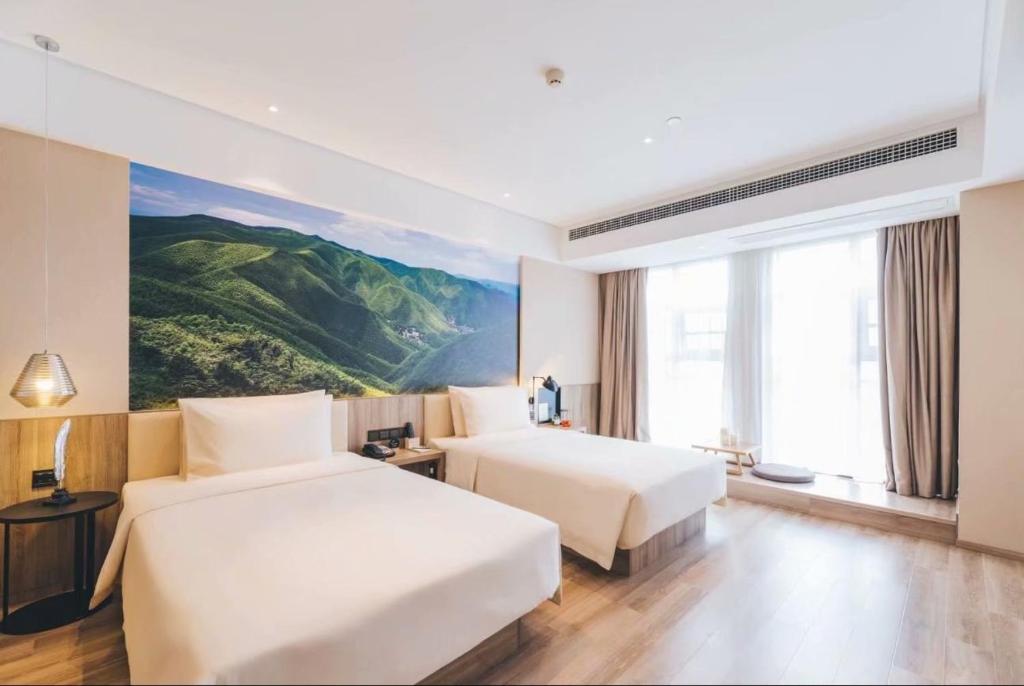 Atour Hotel (Nanjing Shangyuan Street) في نانجينغ: سريرين في غرفة الفندق مع لوحة على الحائط