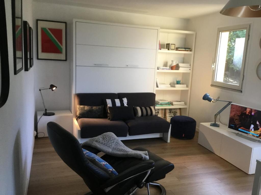 uma sala de estar com um sofá e uma cadeira em Au balcon fleuri em Anglet