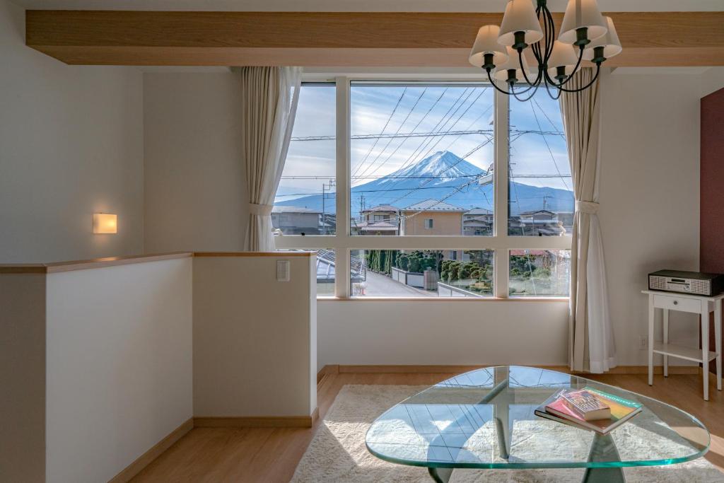 - un salon avec une table en verre et une vue sur la montagne dans l'établissement Villa Fuji Bon Voyage Sora, à Fujikawaguchiko