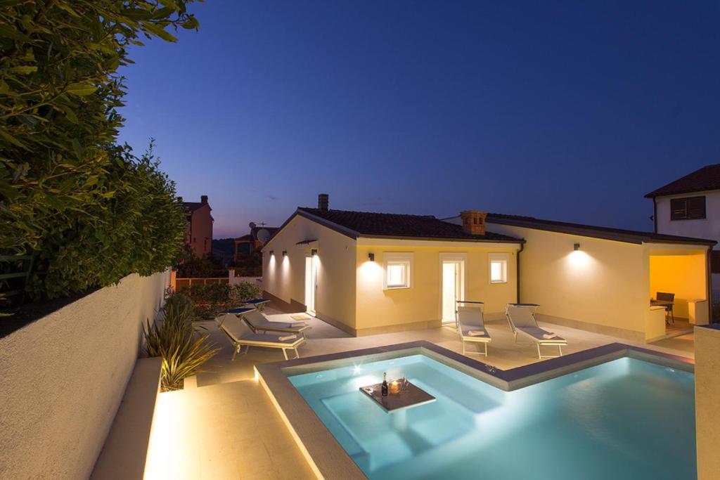 a backyard with a swimming pool at night at Charming villa Manuela with wonderful pool near the beach in Banjole